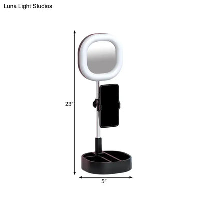 A sleek black and silver led mirror light with circular ring light and adjustable phone holder on slender stand