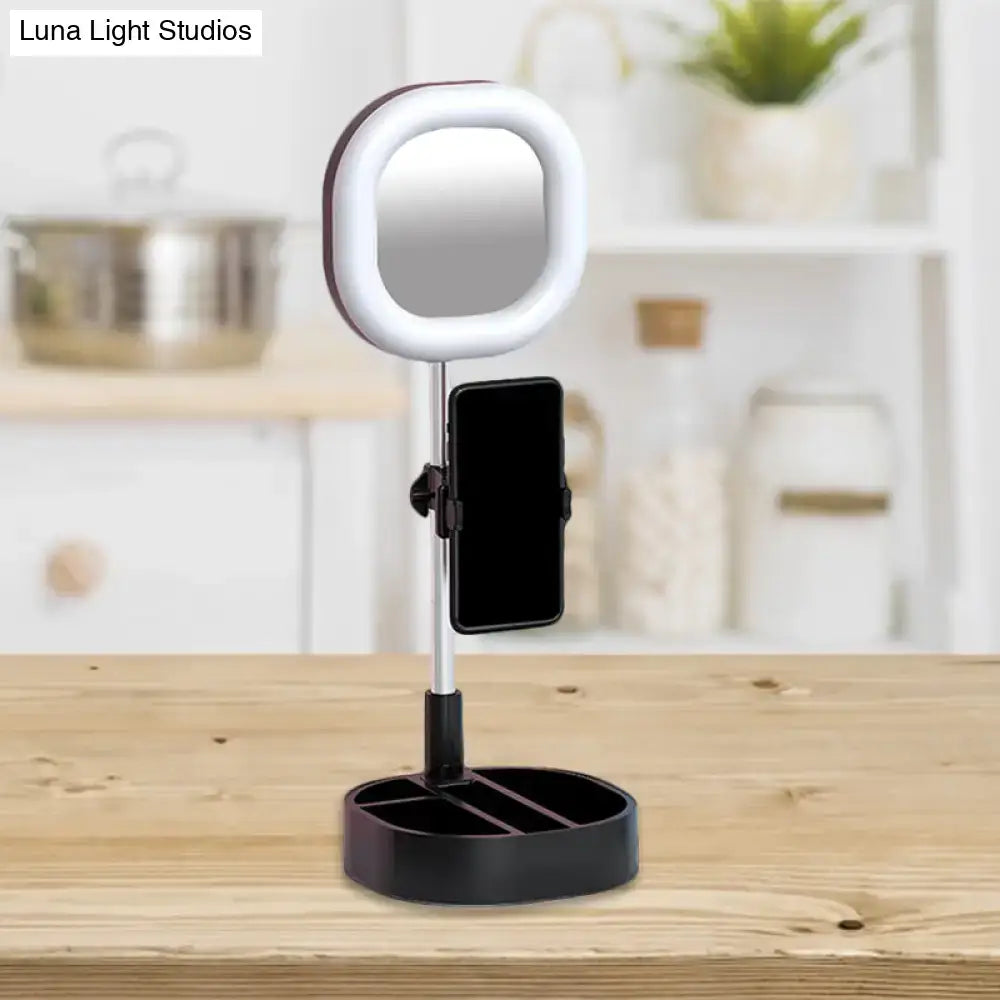 A sleek black and white led mirror light vanity with circular led halo and smartphone holder for bedroom use