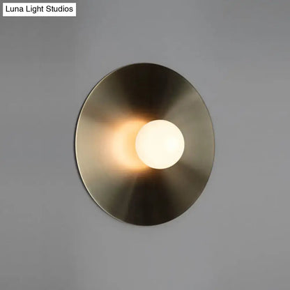 Modern brass-finished wall light fixture with circular design and frosted glass bulb for bedroom sconce lighting
