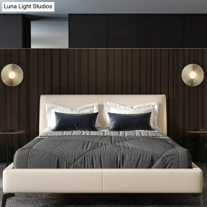 Cream upholstered bed with dark navy pillows paired with simplicity brushed brass circular wall light fixture bedroom sconce