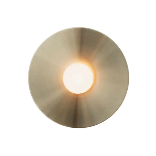 Circular brushed brass wall light fixture with a warm glowing central light ideal as a bedroom sconce wall light