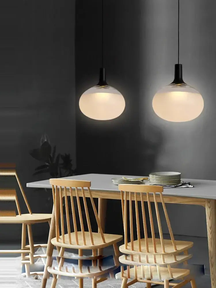 Two sleek black and frosted glass cob led chandelier pendant lights hanging above a dining table for chandelier lighting hanging