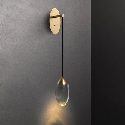 A sleek brass and crystal led wall light with a brushed brass base and teardrop glass pendant for bedroom decorbites crystal led