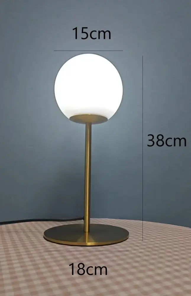 A sleek brass glass ball table lamp with a frosted white shade and minimalist design for bedroom decorbites decor