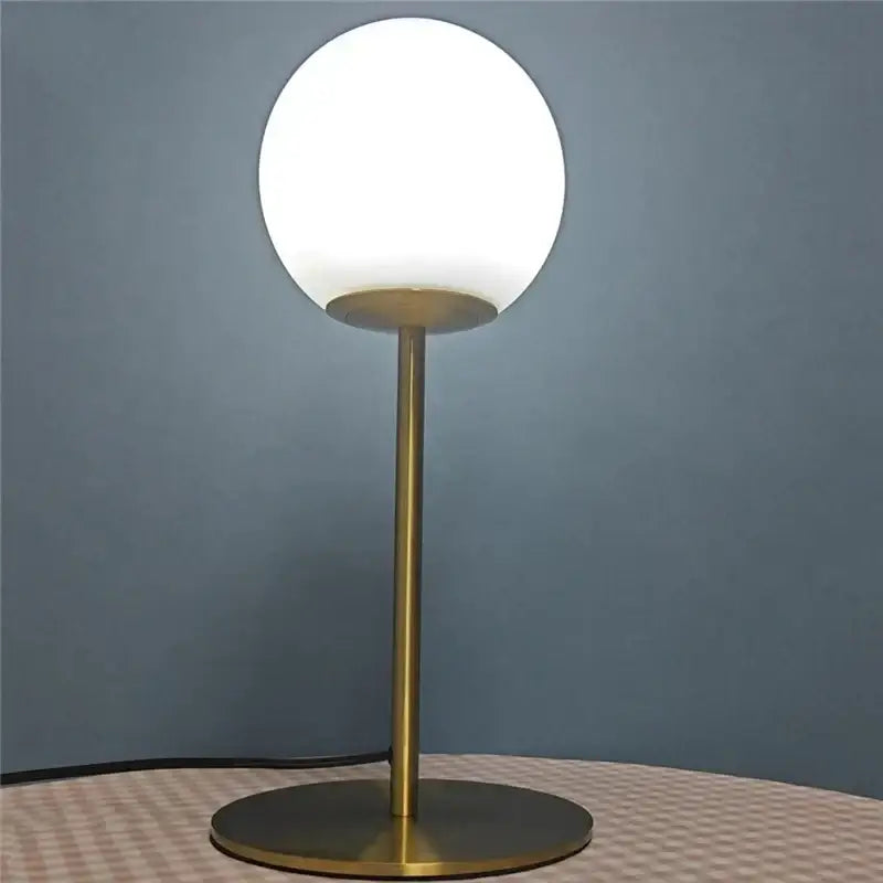 A sleek brass-finished ball table lamp with a frosted glass ball shade for bedroom decorbites glass ball design