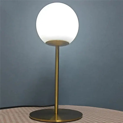 A sleek brass-finished ball table lamp with a frosted glass ball shade for bedroom decorbites glass ball design