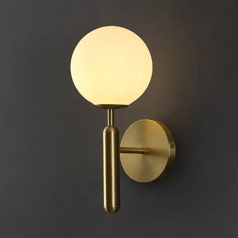 A sleek brass wall sconce lamp with a glowing spherical glass shade for elegant corridor lighting