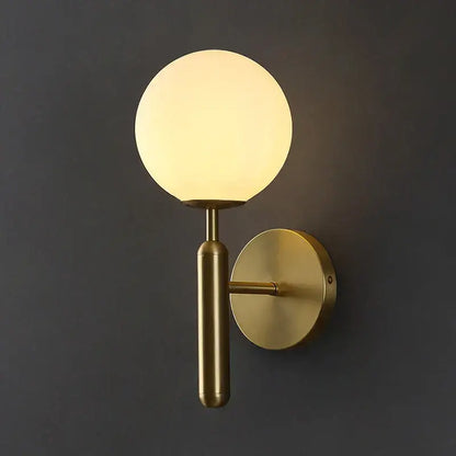 A sleek brass wall sconce lamp with a glowing spherical glass shade for elegant corridor lighting