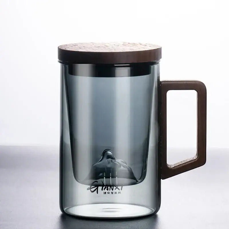 A sleek dark gray double walled glass tea cup with wooden lid and handle for kitchen use