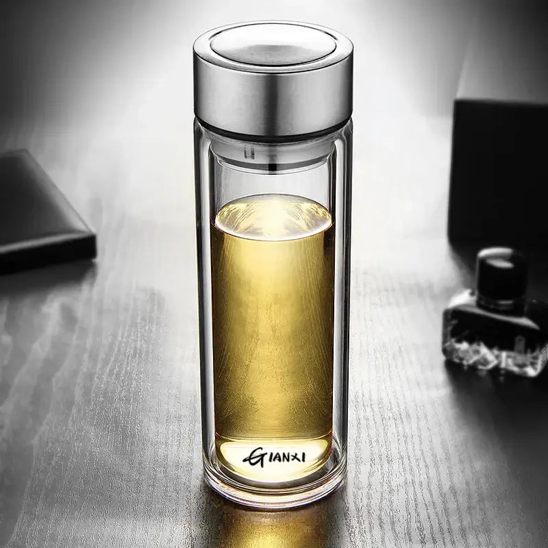 Sleek double-walled glass water bottle with silver lid and base engraved gianxi filled with golden liquid