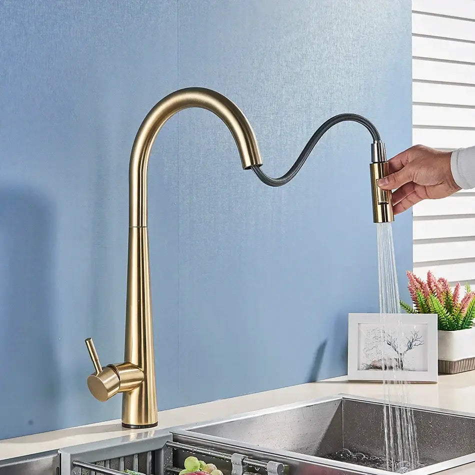 Sleek gold swivel kitchen faucet with a curved gold-toned spout and flexible black pull down sprayer hose decorbites gold swivel