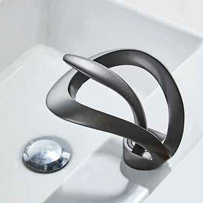 Sleek matte black brass waterfall basin faucet with flowing curves and brushed metallic finish by decorbites black brass
