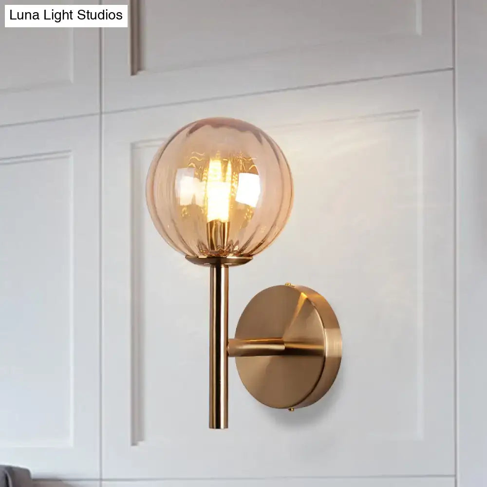 Gold-toned round wall lighting with amber glass globe and brushed metal finish bedside sconce light in red green amber