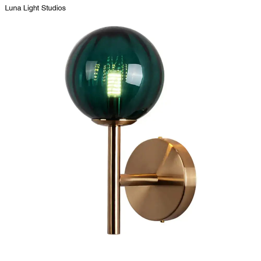 A sleek round wall lighting bedside sconce light with a deep emerald green glass globe and brass stem in red green amber