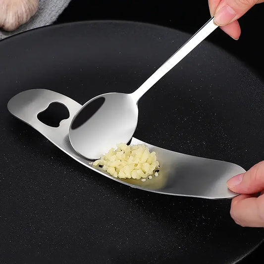 Sleek stainless steel garlic press with integrated spoon and reflective surface by decorbites garlic press