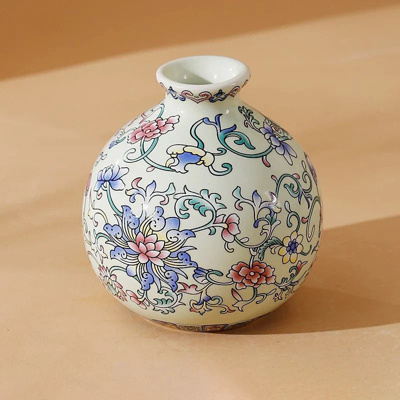 A delicate white ceramic small vase with hand-painted pink blue and green floral patterns for home or office decor