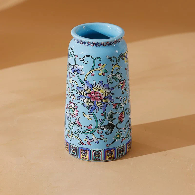 A small light blue ceramic vase with pink purple and gold floral patterns in handmade vintage Chinese enamel glaze