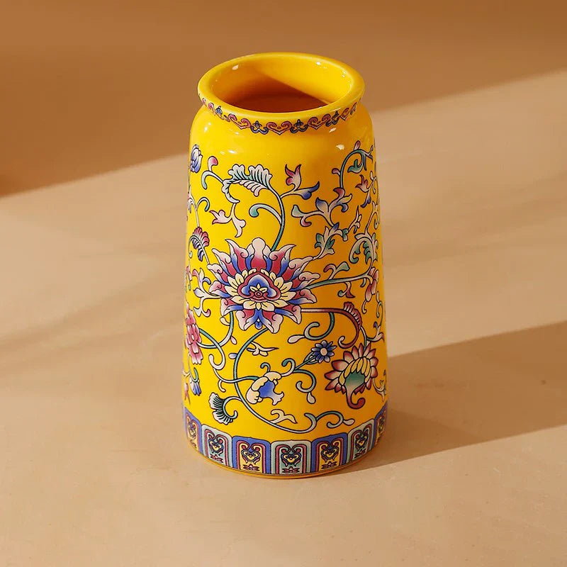 A vibrant yellow small ceramic vase with blue pink and green floral patterns for office and home decoration