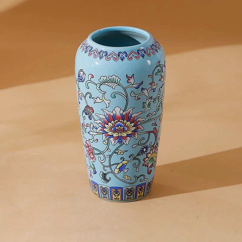 A light blue ceramic vase with intricate pink red yellow and purple floral vine patterns for elegant home decor
