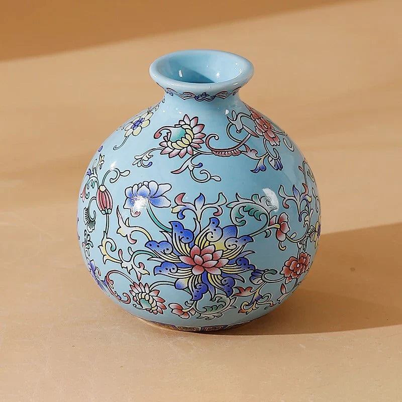 A small light blue ceramic vase with intricate pink purple and gold floral patterns for elegant home decor