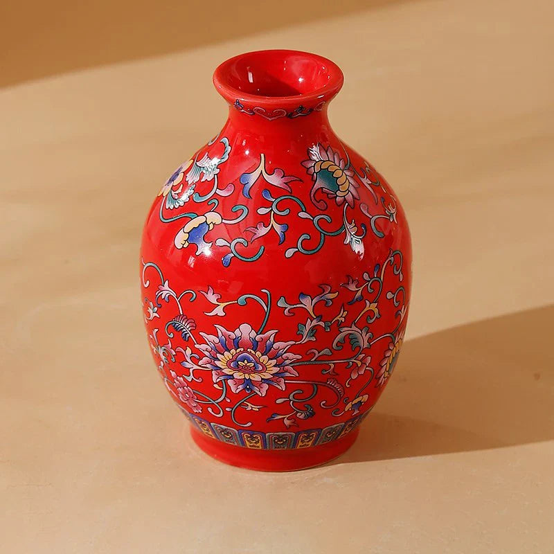 A vibrant red small ceramic vase with intricate blue pink and gold floral patterns for home and office decor
