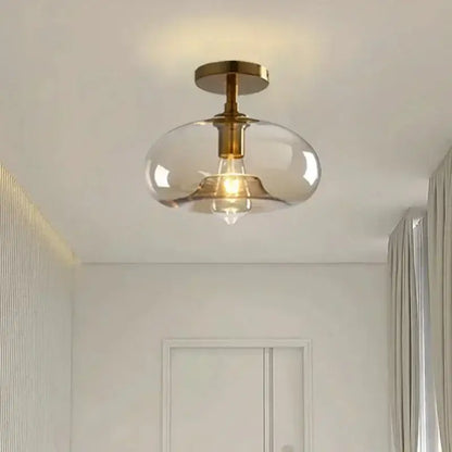 A modern brass-finished pendant light with a clear teardrop glass pendant ideal for dining room lighting