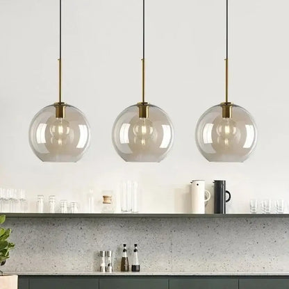 Three modern pendant lights with spherical smoked glass shades and brass-finished metal glass pendant for dining room