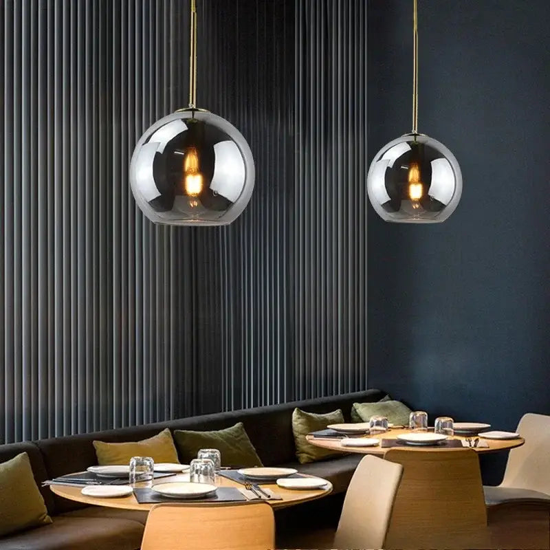 Two smoky gray glass pendant lights with gold-toned chains and iron finish serve as a stylish light source above dining area