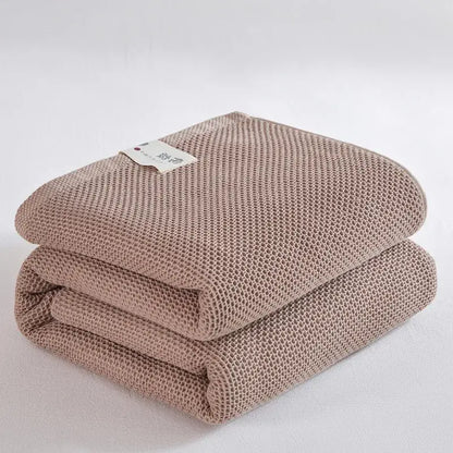 A neatly folded taupe decorbites cotton honeycomb towel blanket with textured mesh pattern for living room couch decor