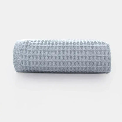 A neatly rolled soft gray cotton waffle towel with a textured grid pattern from decorbites cotton waffle bath set