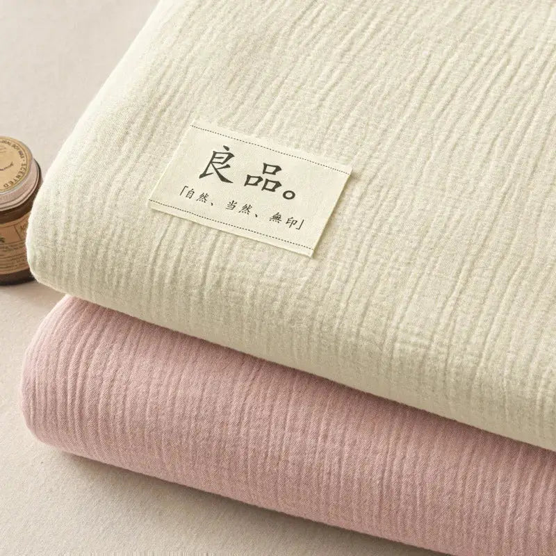 Stacked cotton muslin fabrics in off-white and blush pink paired with soft light gray decorbites cotton fitted sheet