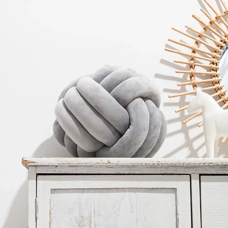 Gray knotted ball round throw pillow made of soft plush fabric ideal for cozy bedroom decor