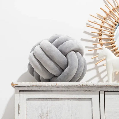 Gray knotted ball round throw pillow made of soft plush fabric ideal for cozy bedroom decor