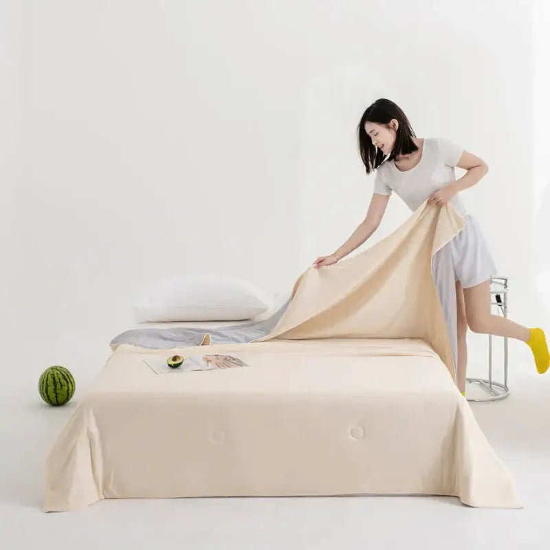 Beige satin bed sheet with subtle button detailing paired with soft teal and gold decorbites cool fibre summer quilt