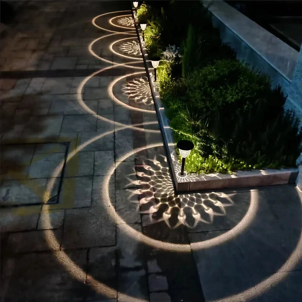 A sleek black outdoor waterproof solar powered pathway light casting intricate circular floral shadows on stone walkway