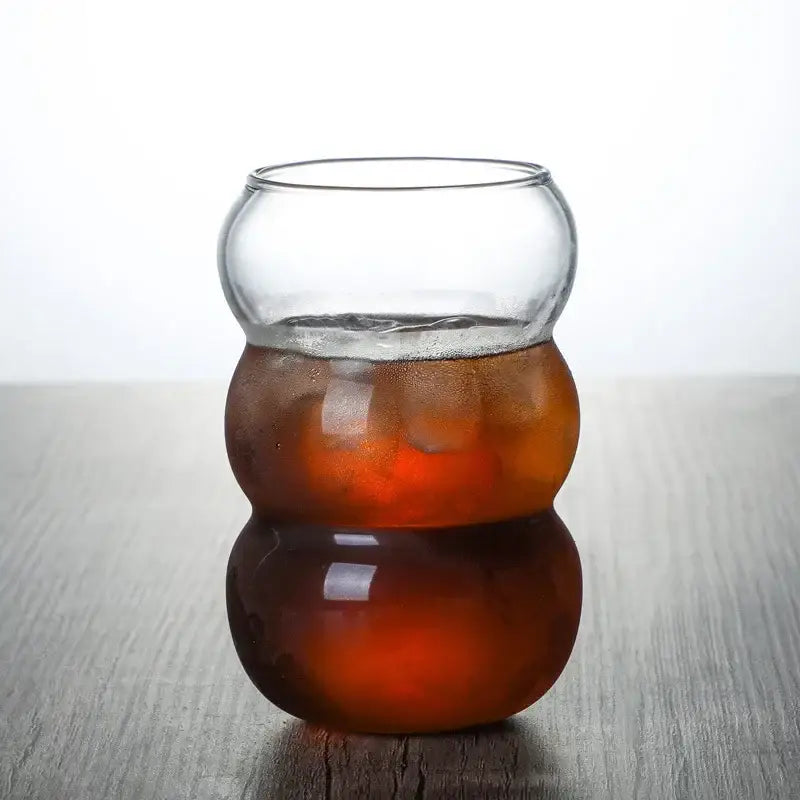Clear glass cold brew coffee cup with a unique segmented bulbous design filled with amber cold brew liquid