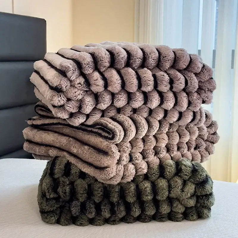 Stacked striped gray and black faux rabbit plush blankets with textured fluffy surface and dark faux pom-pom trim for decorbites dark faux collection