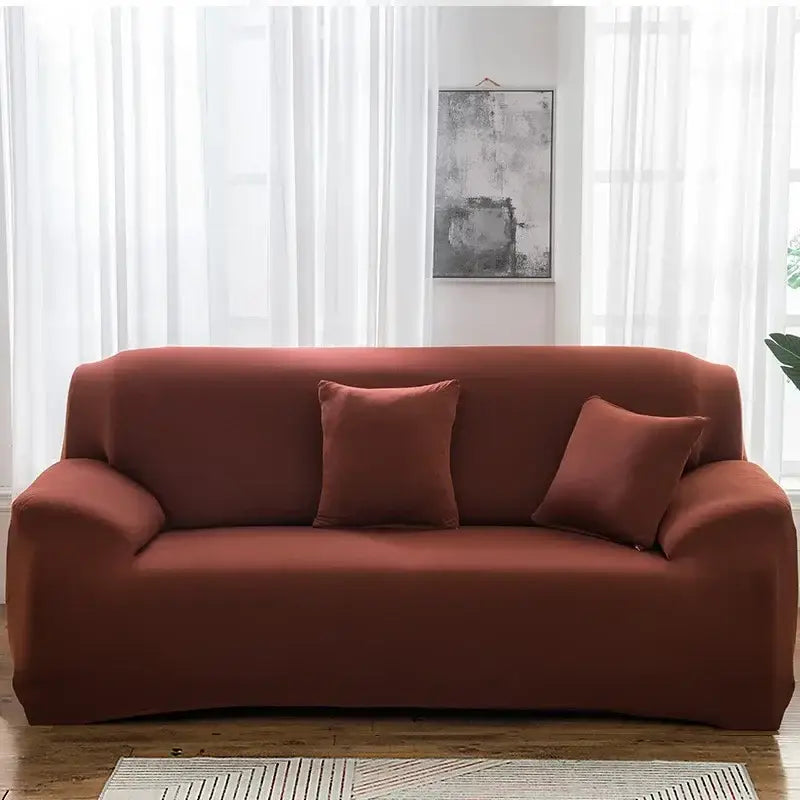 A rust-colored tan stretchy silk sofa cover with matching pillows snugly fits a modern three-seater for living room use