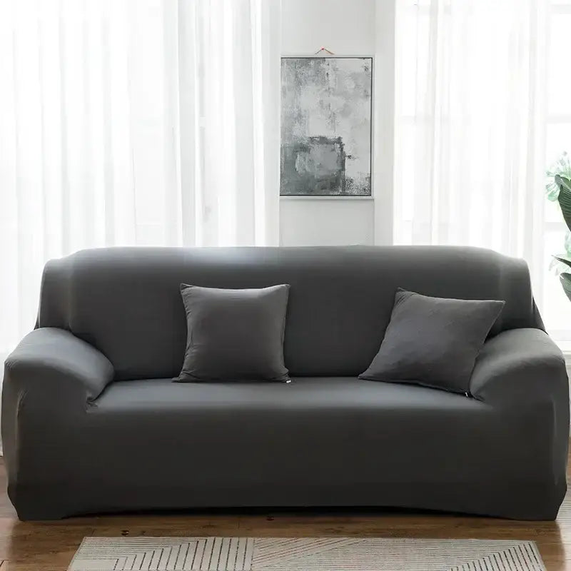 Dark gray stretchy sofa cover with matching pillows snugly fits a three-seater couch for living room use and accent chairs
