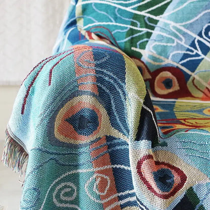 A decorbites knit sofa blanket with a vibrant peacock design in teal orange and red as a sofa blanket cover