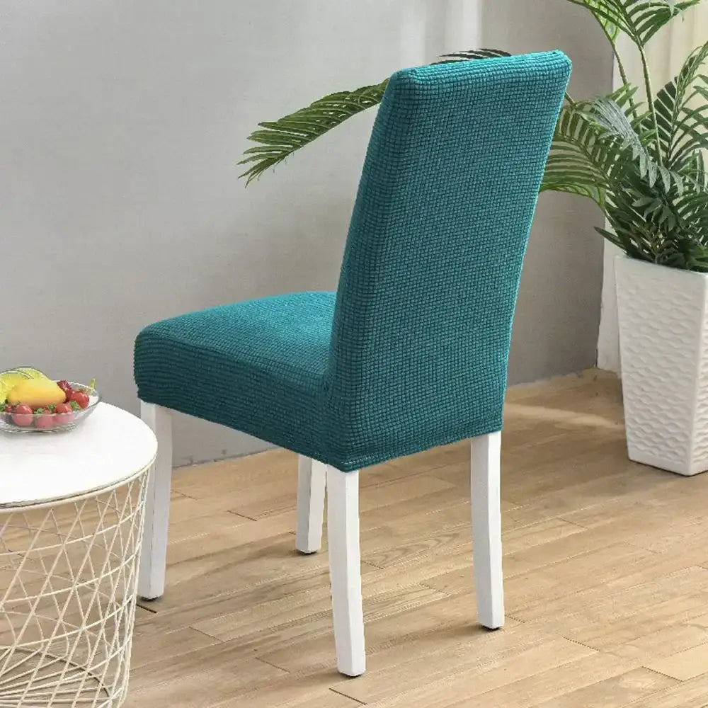 Teal blue quilted chair cover with stretch elastic fit over white wooden dining chair by decorbites