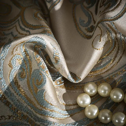 Beige silk fabric with intricate teal and gold paisley embroidery and cream pearls on a 200s egyptian cotton bedding set