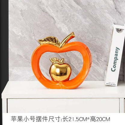 Teal and orange gold plated ceramic apple storage box with an orange apple sculpture and smaller golden apple inside