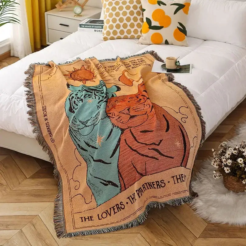 A beige decorbites knitted nordic outdoor sofa throw with teal and orange tigers under a sun motif labeled the lovers