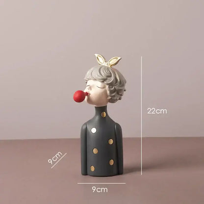 A gray ceramic bowknot girl resin figurine with gold polka dots and bunny ears blowing red bubblegum on a gold tray