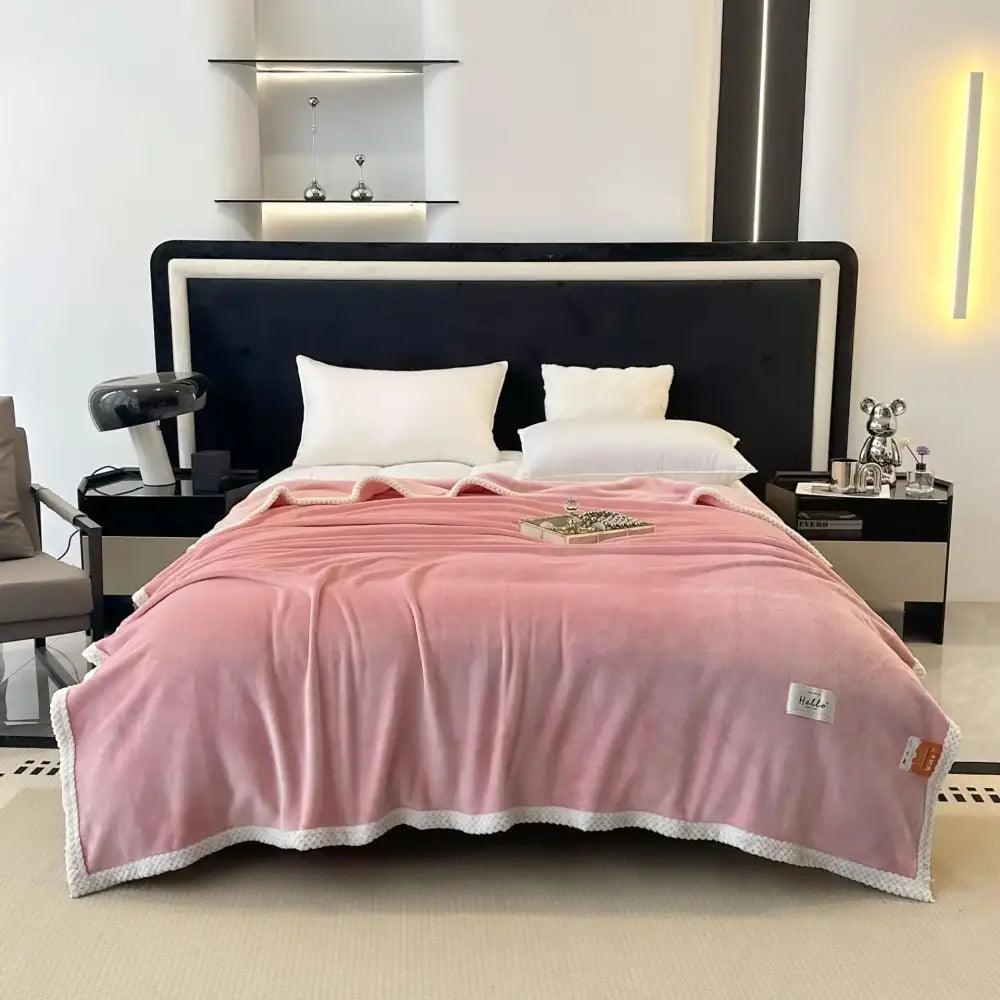 A soft pink cozy flannel nap blanket with a white textured border and subtle brand tags on the corner