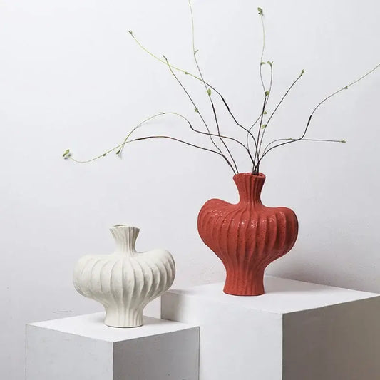 A terracotta heart-shaped ceramic fringe heterophore vase with vertical ridges holding slender green branches for decorbites living room decor