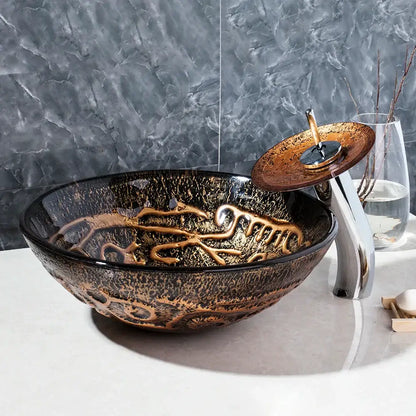 Textured black and gold glass wash basin set featuring a glossy vessel sink with gold leaf patterns and bronze faucet