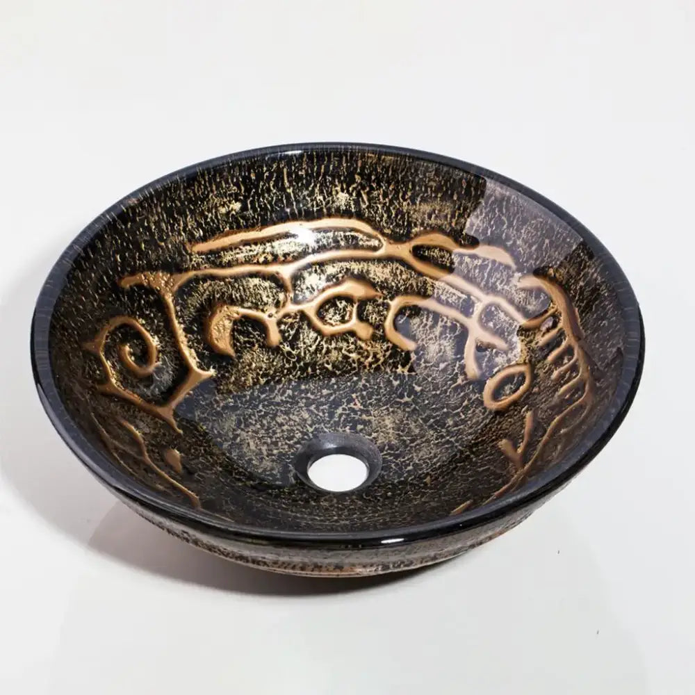 A sleek round glass wash basin with dark crackled finish and gold swirling patterns in a textured black and gold basin set