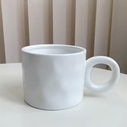 A minimalist white ceramic coffee mug with a smooth glossy finish and rounded handle for kitchen use